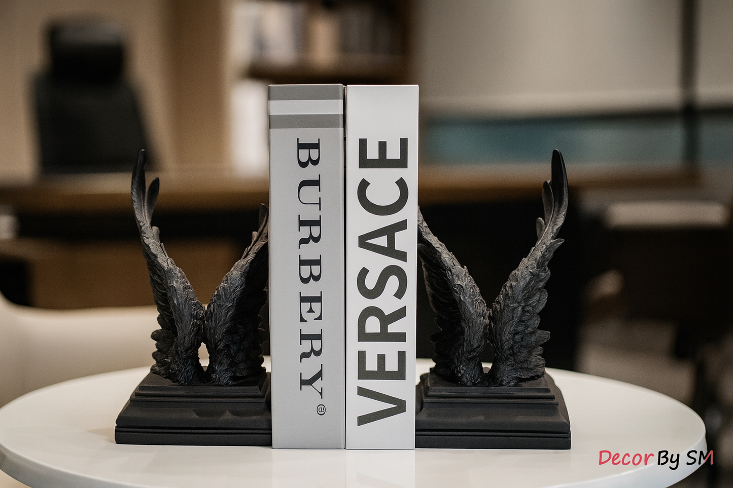 Black wing bookends with books in executive office environment
