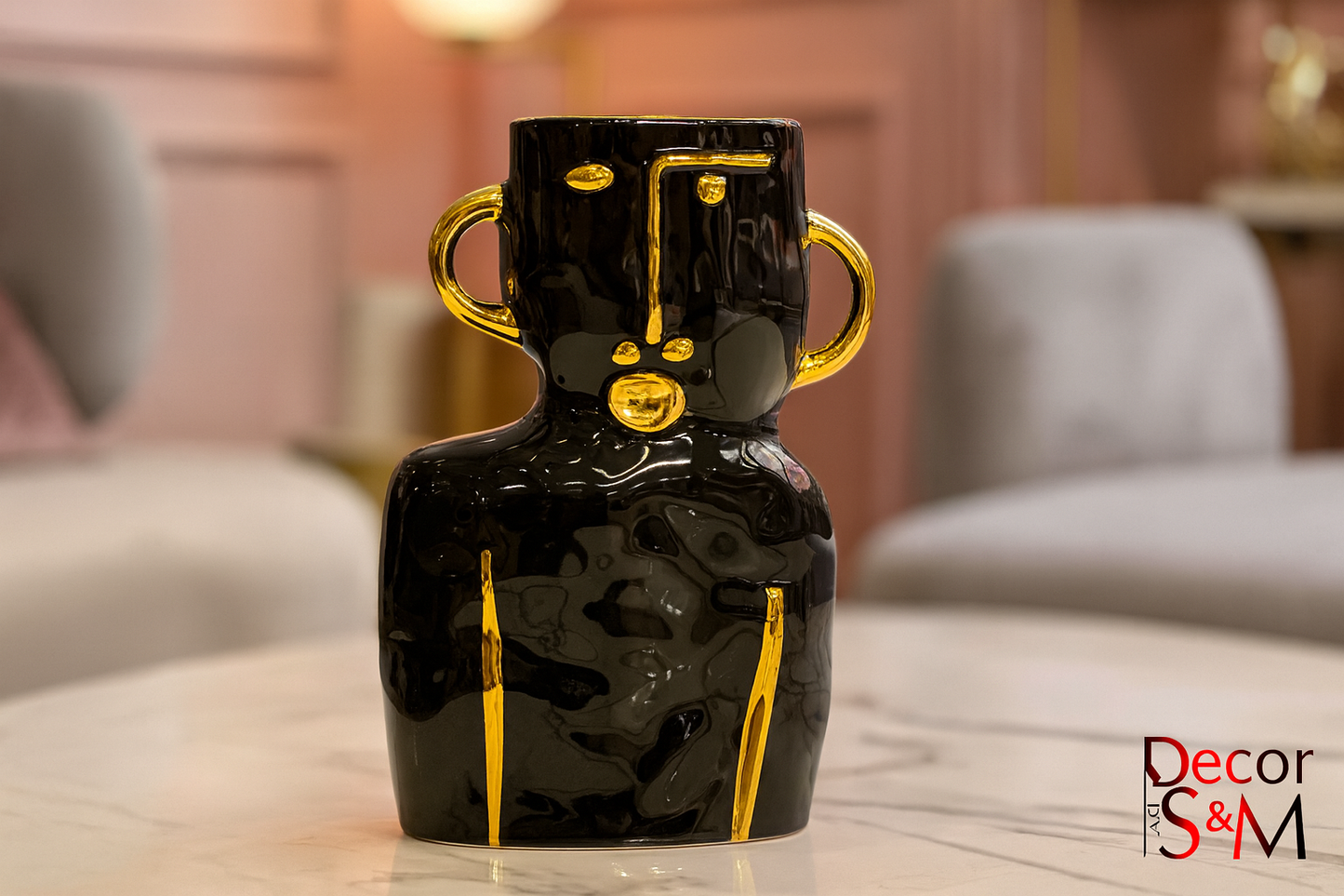 Black ceramic vase with golden handles on glass table in contemporary living space