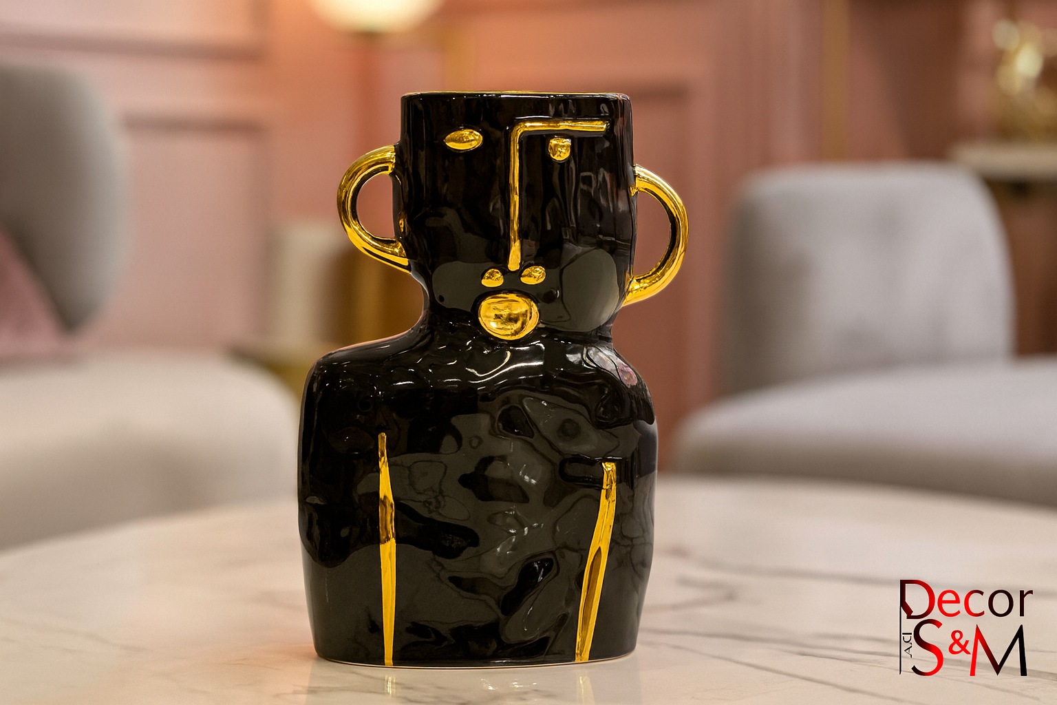 Black ceramic vase with golden handles on glass table in contemporary living space
