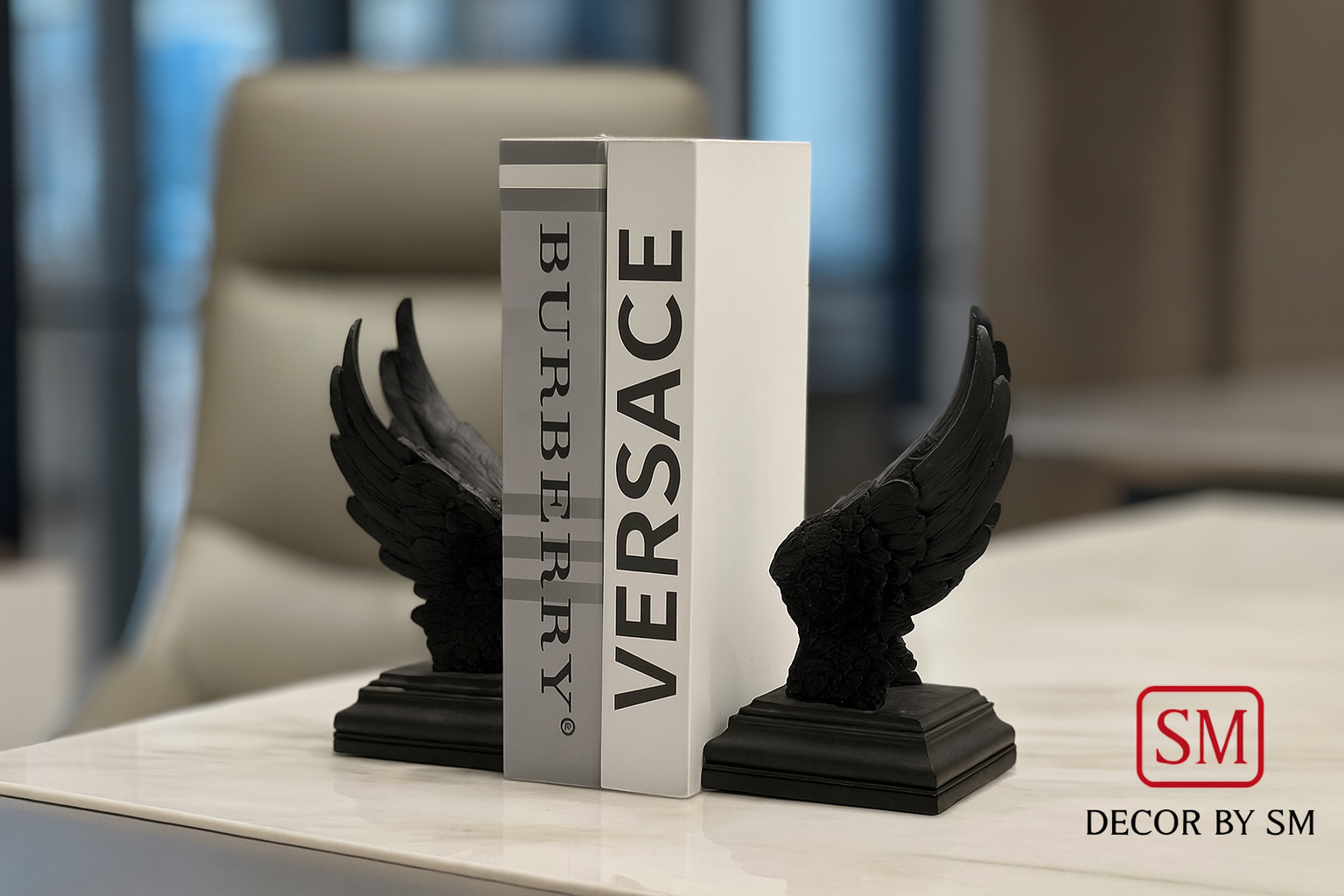 Black wing bookends with books on modern office desk