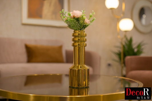 Golden column vase with pink flowers on glass table in contemporary living space