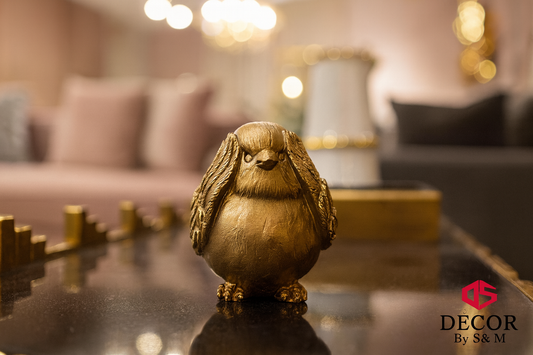 Golden round bird figurine on glass table in contemporary living space