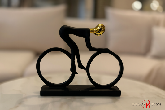 Modern black cyclist sculpture with golden accents on glass coffee table