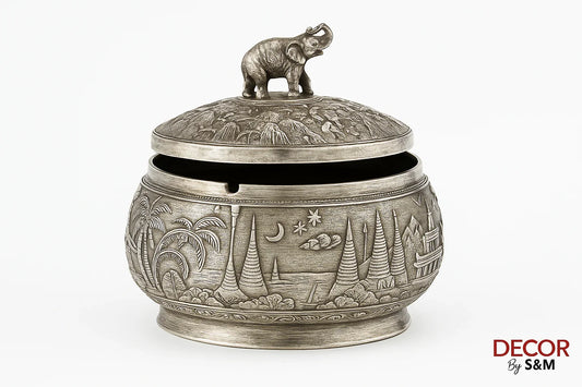 Ornate brass vessel with intricate engravings and elephant lid handle on white background