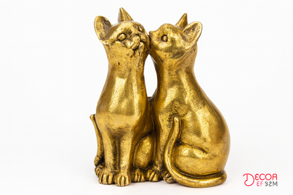 Pair of golden cat figurines on white background