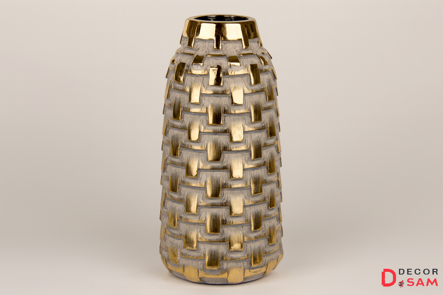 Tall metallic vase with basket-weave pattern on warm white background