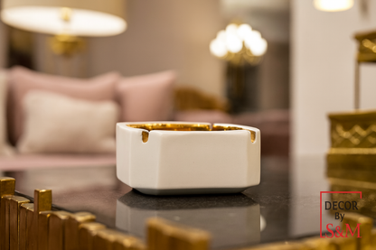 White and gold square decorative bowl on glass table in contemporary living space