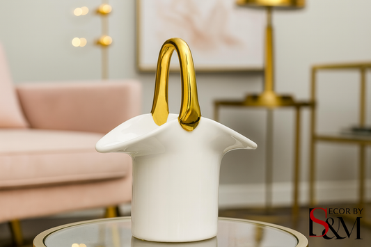 White ceramic vessel with golden handle on glass table in contemporary living space