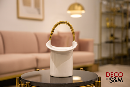 White ceramic vessel with golden handle on glass table in contemporary living space